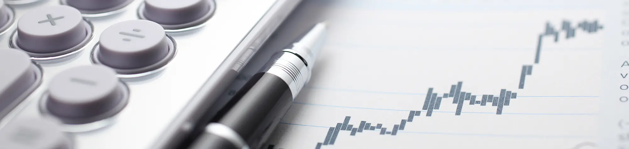 Calculator, pen, and financial graph on paper.